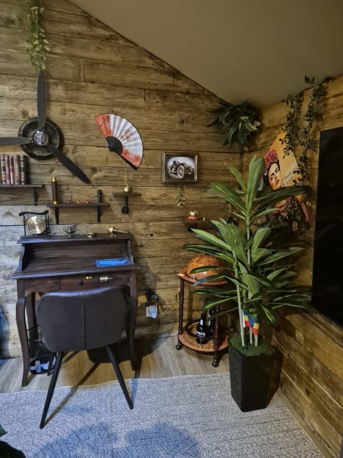 Chambre vintage à l'Escape Hotel avec murs en bois, horloge hélice d'avion, bureau rétro, plante en pot et