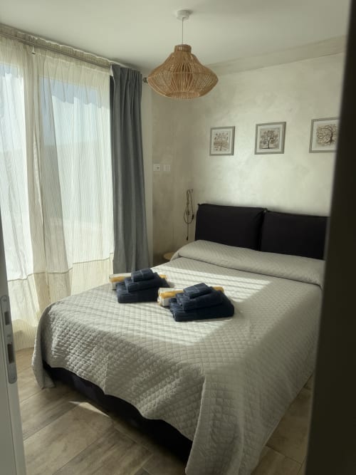 Modern bedroom in Sardinia Holidays BnB with queen bed, black headboard, woven pendant light, and sea view balcony in Torpè,