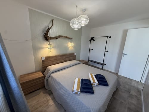 Modern bedroom in Sardinia Holidays villa with queen bed, sea view, pendant lights, and contemporary furnishings