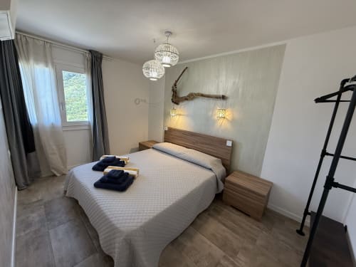 Modern bedroom in Sardinia Holidays villa apartment with sea view, queen bed, pendant lights, and private balcony in Torpè,