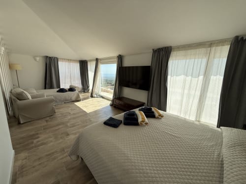 Spaziosa Suite Principale a Sardinia Holidays con vista mare, letto, zona living e terrazza panoramica a Torpè