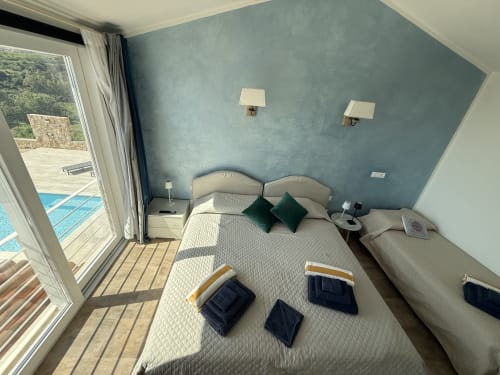 Camera da letto shabby chic di lusso a Sardinia Holidays con vista sul mare, parete blu, letto matrimoniale e accesso alla piscina a Torpè