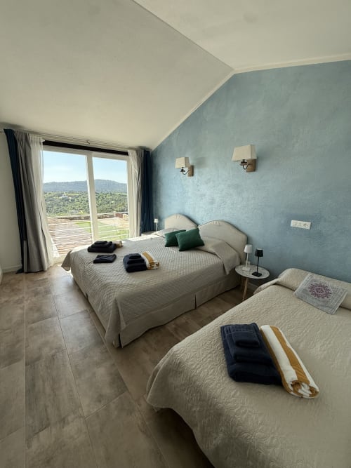 Camera matrimoniale in stile shabby chic a Sardinia Holidays con vista mare, due letti, balcone con vista sul verde e parete azzurra