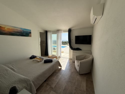 Modern bedroom with double bed, TV, and direct access to pool terrace at Sardinia Holidays, Torpè