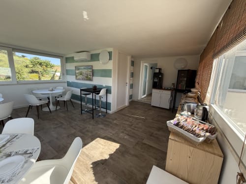 Modern kitchen-dining area at Sardinia Holidays B&B with ocean views, white dining chairs, bar seating, and appliances