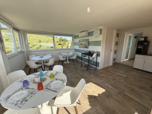 Spacious dining area at Sardinia Holidays BnB in Torpè with multiple tables, white chairs, ocean views, and modern amenities
