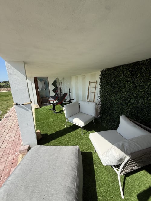 Private veranda at Sardinia Holidays with lounge chairs, green hedges, and lawn overlooking ocean in Torpè