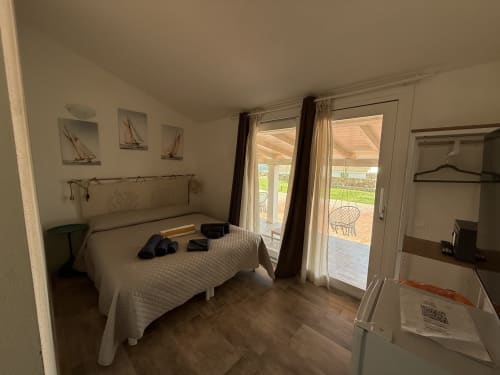 Bright bedroom with double bed, private veranda doors, and ocean view at Sardinia Holidays B&B in Torpè, Italy