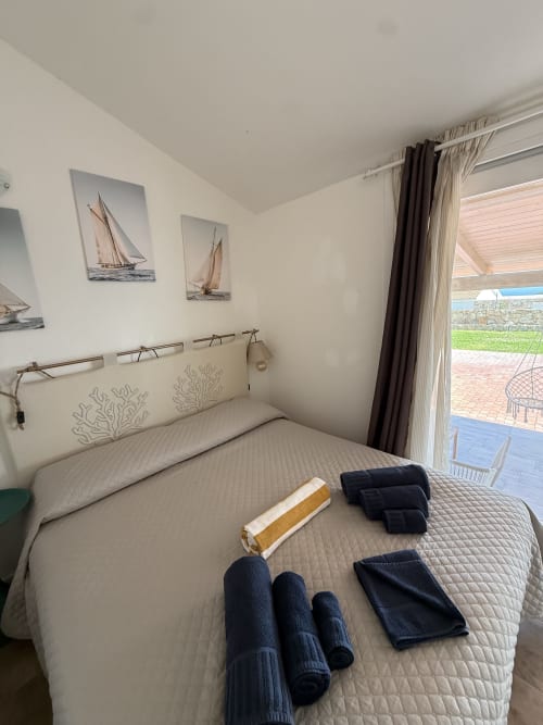 Bedroom with ocean view at Sardinia Holidays in Torpè with towels on bed and sailboat artwork