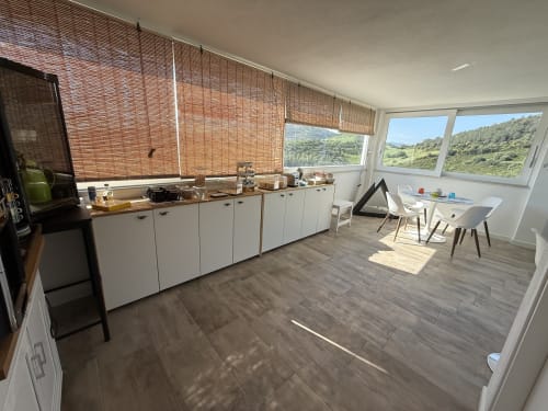 Modern kitchen and dining area in NAVY ROOM at Sardinia Holidays with scenic garden views through large windows, white