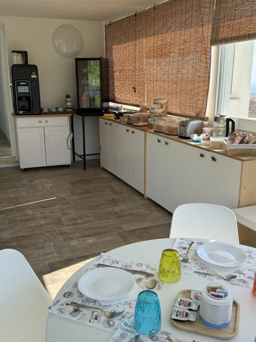 Modern kitchenette with white cabinetry, dining table set for two, and ocean view at Sardinia Holidays B&B in Torpè