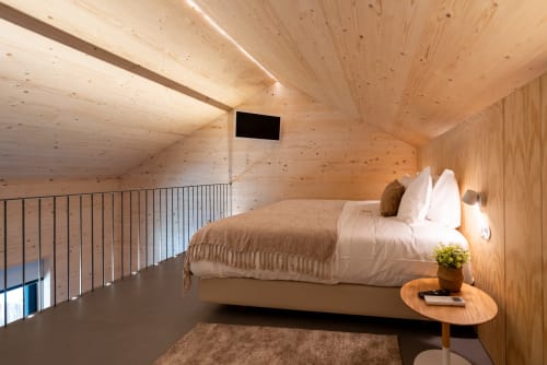 Quarto moderno em madeira na Quinta Das Pirâmides B&B com roupa de cama branca, mezanino e iluminação ambiente aconchegante em Vila Nova