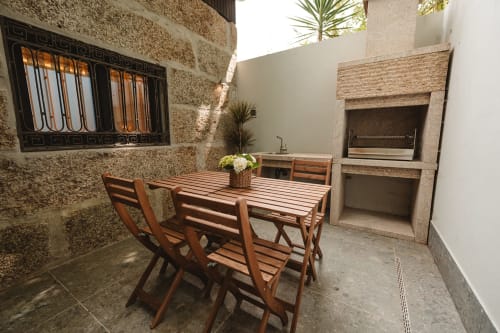 Pátio da Quinta Das Pirâmides com mesa de jantar em madeira, cadeiras e churrasqueira embutida em Vila Nova de Famalicão