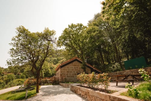 Lodge de pedra cercado por árvores frondosas na Quinta Das Pirâmides, pousada campestre portuguesa em Vila Nova de