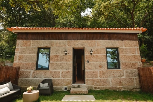 Casa de pedra Quinta Das Pirâmides com telhado laranja e área de estar ao ar livre em Vila Nova de Famalicão