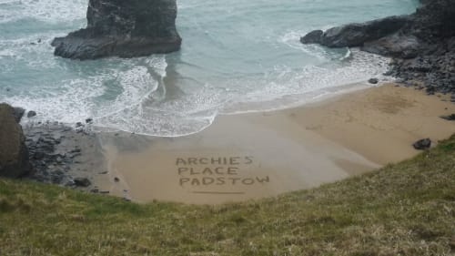 Archies Place Padstow beach cove with turquoise sea, golden sand, and dark rocky outcrops