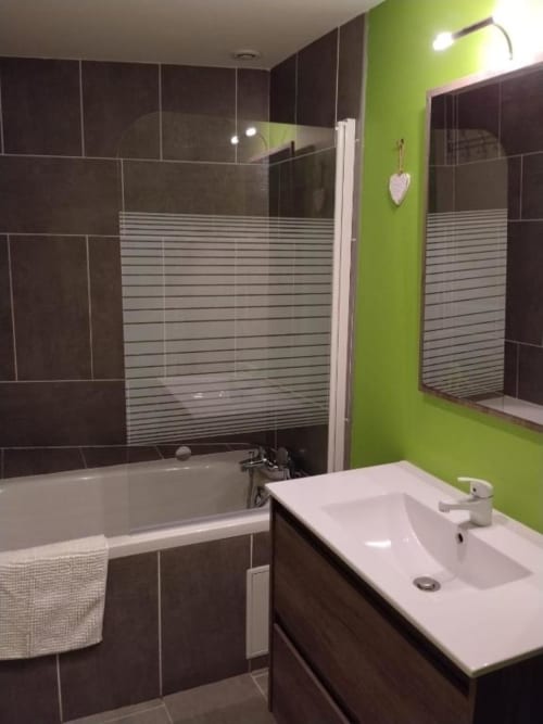 Modern bathroom at La Pause Landaise with bright lime green walls, dark tiled shower, white sink and contemporary fixtures