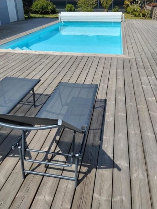 Poolside lounge chairs on wooden deck with turquoise pool and white cover at La Pause Landaise, Magescq