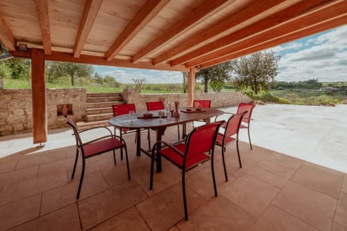 Terrasse couverte avec chaises rouges et table à manger vue sur la campagne à Vila Cabanes 46, Le Montat, Lot
