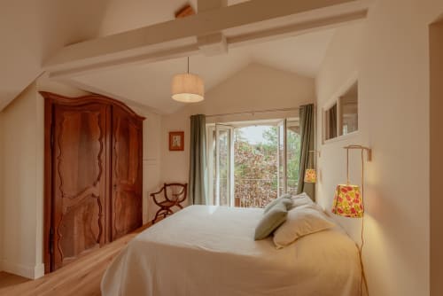 Chambre lumineuse avec armoire en bois, lit blanc et vue sur le jardin à la Villa Cabanes 46 au Montat, Lot