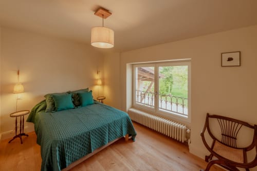 Chambre spacieuse avec literie bleu-vert, mobilier en bois et vue sur le jardin à la villa Vila Cabanes 46 dans le Lot, France