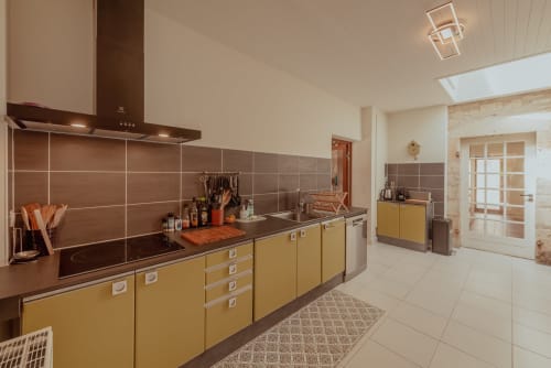 Cuisine moderne aux armoires jaunes, dosseret en carrelage brun et électroménagers en acier inoxydable à Vila Cabanes 46 au Montat