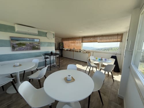 Modern tropical bedroom at Sardinia Holidays with round white tables, kitchen, and ocean views from Torpè