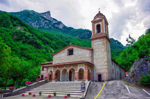 Chiesa in pietra storica con campanile circondata da verdi montagne vicino a Villa Andreina ad Amandola, Italia
