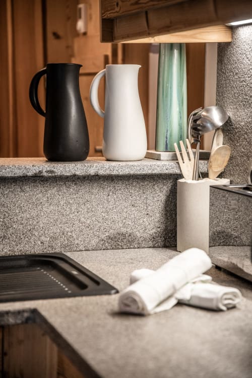 Modern kitchen counter at Le Chalet Mont-Blanc with black and white pitchers, cooking utensils, and mountain view backdrop