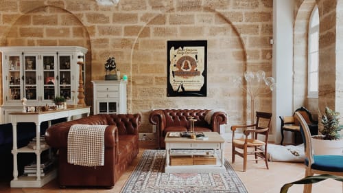 Élégant salon du Pavillon Des Millésimes à Lussac avec canapé Chesterfield en cuir marron, murs en pierre apparente
