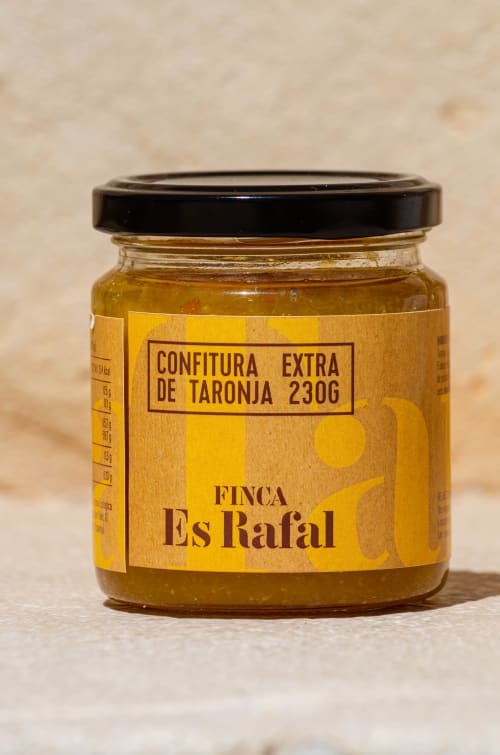 Finca Es Rafal orange marmalade jar with black lid on beige background, Montuïri