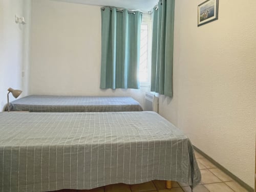 Chambre twin avec courtepointes à rayures vertes et rideaux à la fenêtre à l'appartement LOCADIGNE à Digne-les-Bains