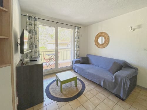 Séjour lumineux à LOCADIGNE Digne-les-Bains avec canapé bleu, TV, portes-fenêtres sur balcon avec vue montagne, et mobilier moderne