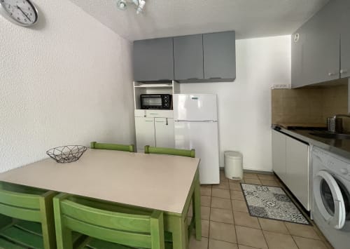 Cuisine moderne avec table verte, électroménagers blancs et caissons gris, appartement LOCADIGNE à Digne-les-Bains