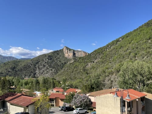Vue montagnarde du village de Digne-les-Bains avec ses appartements aux toits rouges nichés dans une vallée verdoyante sous des pics rocheux