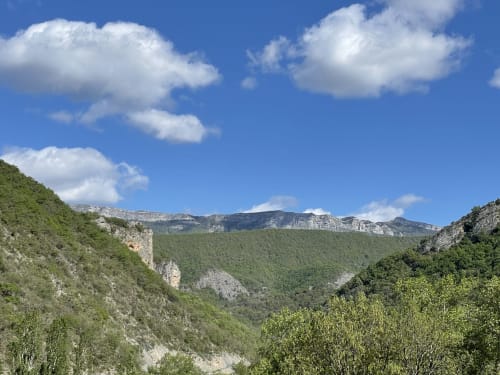 Vue panoramique de la vallée montagnarde depuis l'appartement Vallon des Sources à Digne-les-Bains avec pentes boisées et pics calcaires