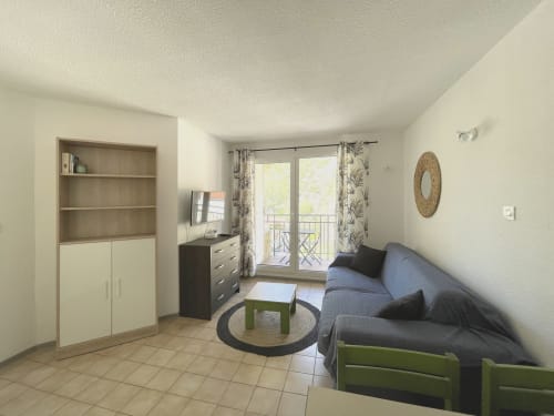Salon moderne à Digne-les-Bains avec canapé, rangements, TV et accès balcon vue montagne