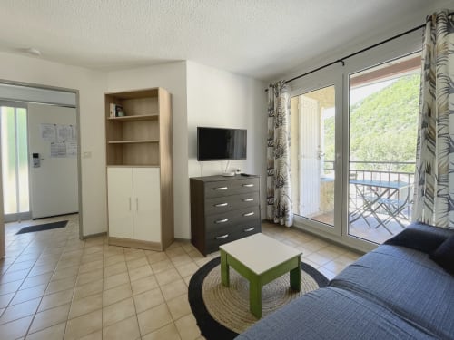 Salon moderne à LOCADIGNE Digne-les-Bains : canapé, TV, rangements, accès balcon et vue sur les montagnes