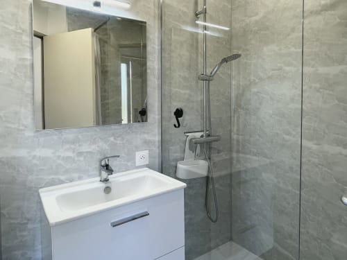 Salle de bain moderne de l'appartement LOCADIGNE à Digne-les-Bains avec vasque blanche, miroir et douche pluie