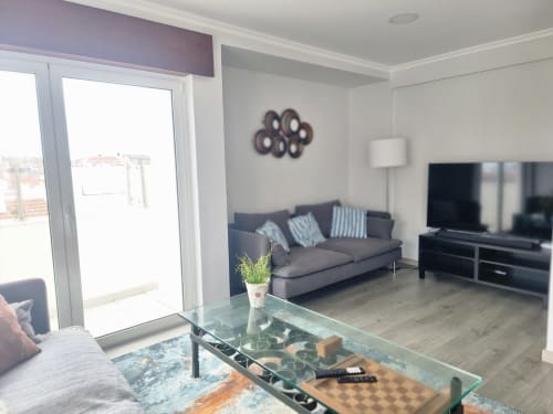 Sala de estar moderna na Casa da Barroca, Ericeira com sofá cinzento, mesa de café em vidro, TV de ecrã plano e vistas da cidade