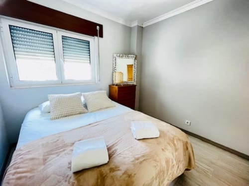 Quarto aconchegante na Casa da Barroca em Ericeira com cama de casal, almofadas decorativas, vista da cidade e comodidades modernas