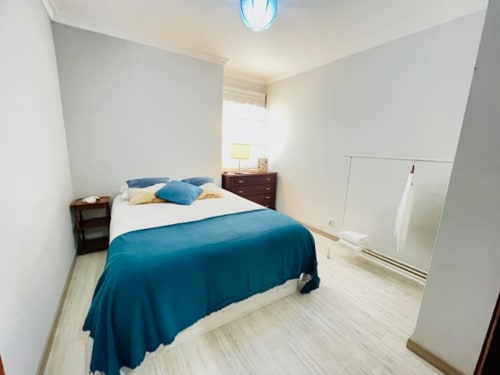 Quarto luminoso da Propriedade Ericeira com roupa de cama azul, móveis em madeira e comodidades modernas em Casa da Barroca