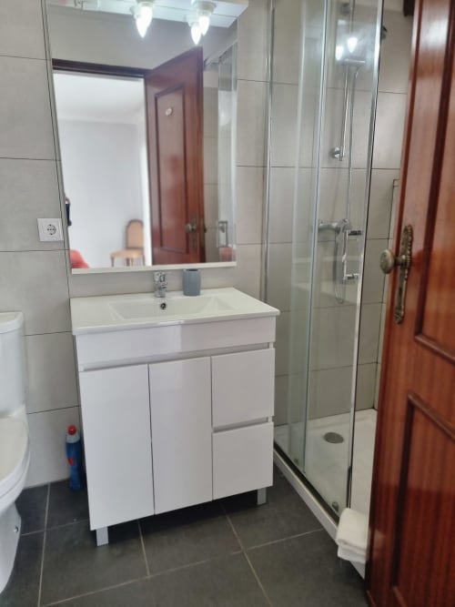Banheiro moderno com lavatório branco, espelho e box de vidro na Casa da Barroca, Ericeira