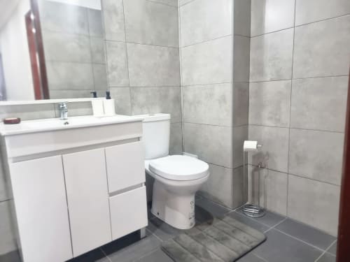 Banheiro moderno da Casa da Barroca, Ericeira com penteadeira branca, sanita, azulejos cinzentos e piso escuro