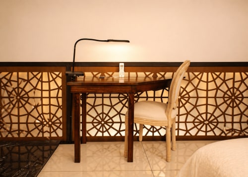 Coin bureau moderne dans la chambre de l'hôtel Villa Merida avec panneaux géométriques en bois, lampe, chaise et télécommande