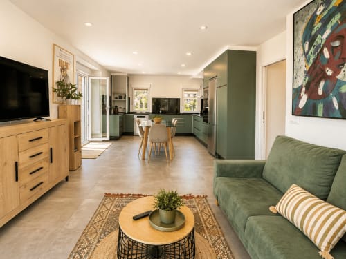 Moderno apartamento diáfano en Baiona con cocina verde, muebles de madera, sofá verde y comedor con vistas al mar