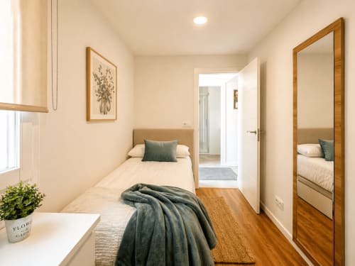Dormitorio acogedor en el apartamento Portaliña, Baiona con cama individual, espejo de madera, planta y acceso al baño privado