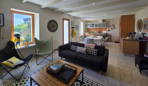Modernes Wohnzimmer in der Villa La Maison du Pêcheur in Les Villes Du Bord De Mer, Guidel, mit schwarzem Sofa und Gartenblick