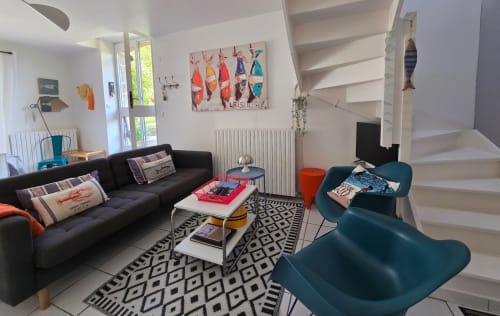 Modernes Wohnzimmer der Villa in Les Villas Du Bord De Mer mit schwarzem Sofa, Sessel in Blaugrün, gemustertem Teppich und Treppe in Guidel