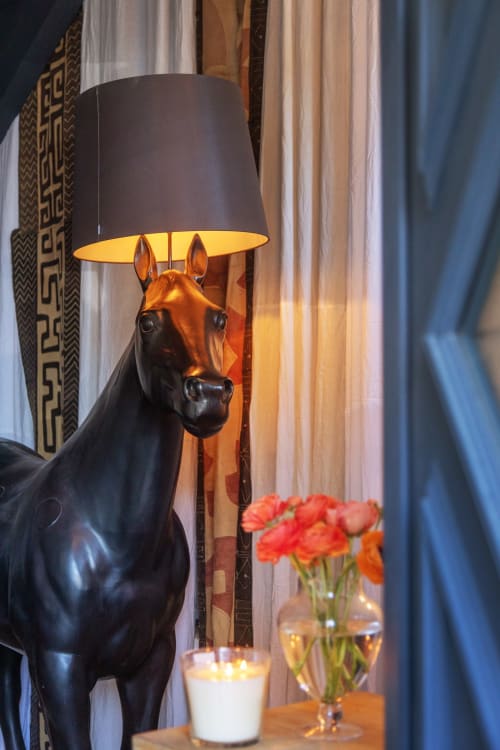 Black horse lamp with yellow shade at Alombre B&B, Lectoure France, beside red flowers
